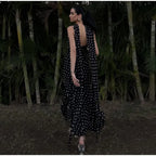 Woman in a black polka dot dress walking through a forest