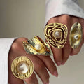Gold rings with pearl centers on a hand against a neutral background