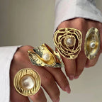 Gold rings with pearl centers on a hand against a neutral background