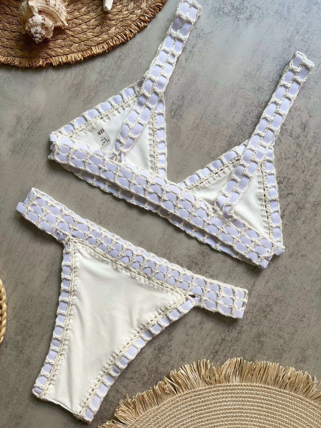 White bikini set with embellishments on a textured surface