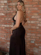 Woman in a black dress standing against a brick wall