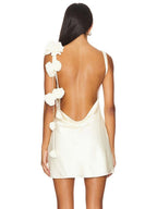 Back view of a cream-colored dress with floral details on a white background