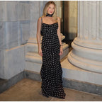 Woman in a black and white polka dot dress standing in a marble interior setting.