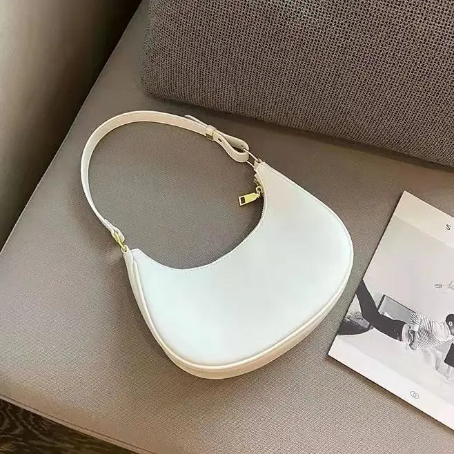 White handbag on a gray surface with a magazine underneath