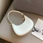 White handbag on a gray surface with a magazine underneath