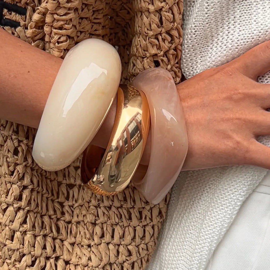 Close-up of a person's wrist wearing two bangles on a textured surface.