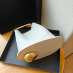 White and gold decorative object on a black tray with a neutral background