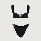 Black bikini set with gold accents on a light gray background
