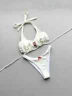 White bikini set with red bows on a gray background