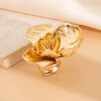 Gold flower-shaped ring on a beige background