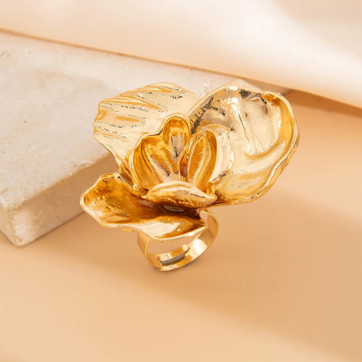 Gold flower-shaped ring on a beige background