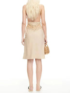 Woman wearing a beige dress with lace detailing on a white background