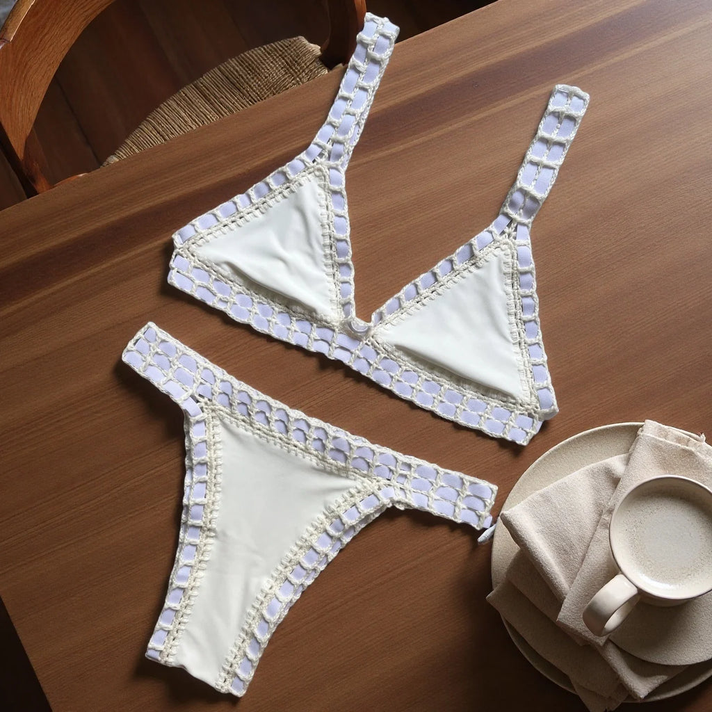 White bra and panties set with decorative trim on a wooden table.