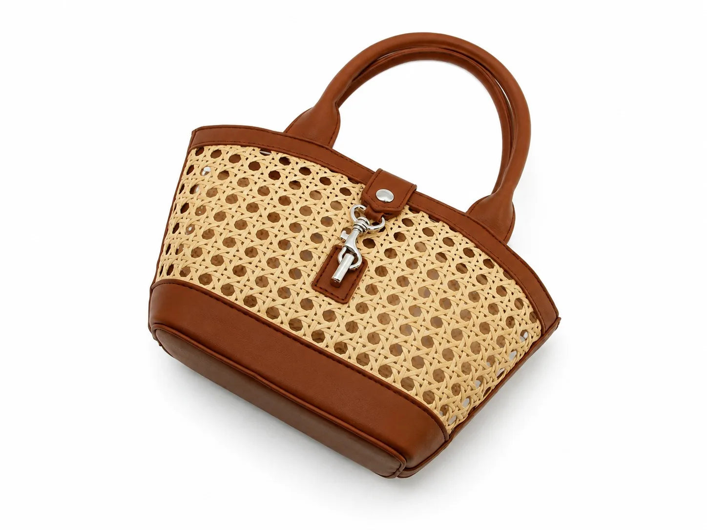 A structured handbag with a brown faux-leather body, handles, and base, combined with a natural beige woven rattan panel featuring a circular dot pattern. It has a brown leather strap closure with a silver-tone key ring and key charm, photographed on a white background.