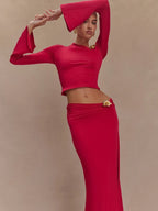 Woman wearing a red outfit with a matching headpiece against a beige background