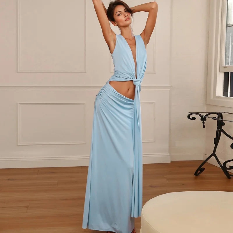 Woman wearing a light blue dress in an elegant room with wooden floor and white walls.