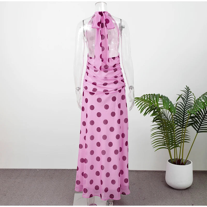 Mannequin wearing a pink polka dot dress with a plant in the background