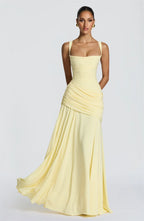 Woman wearing a light yellow evening gown on a plain background