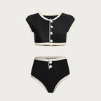 Black and white two-piece swimsuit with button details on a light gray background