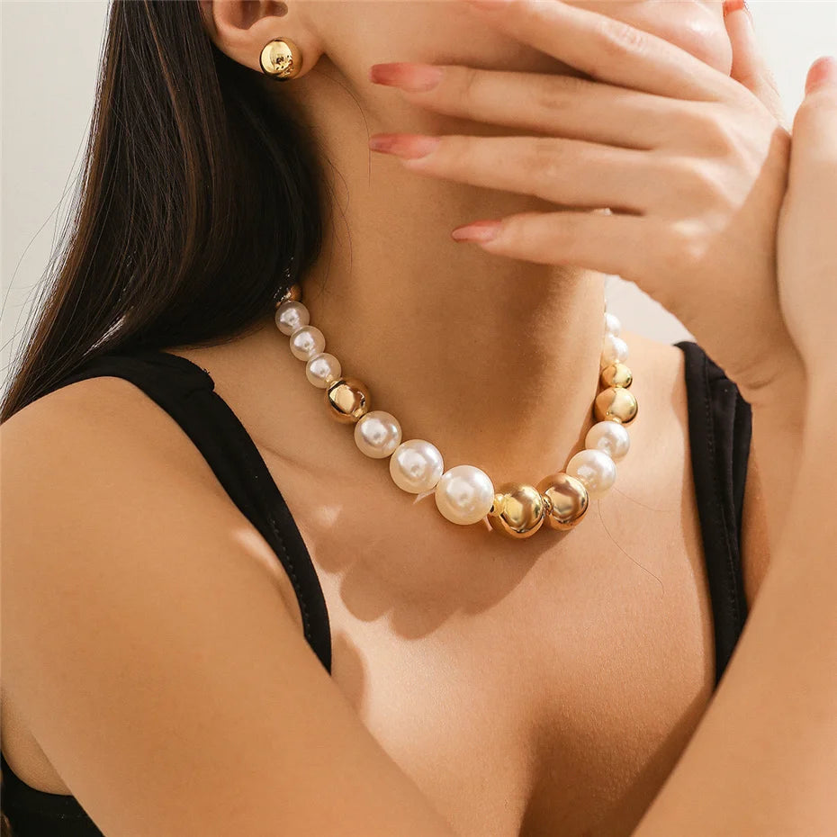 Woman wearing a pearl and gold necklace with matching earrings.