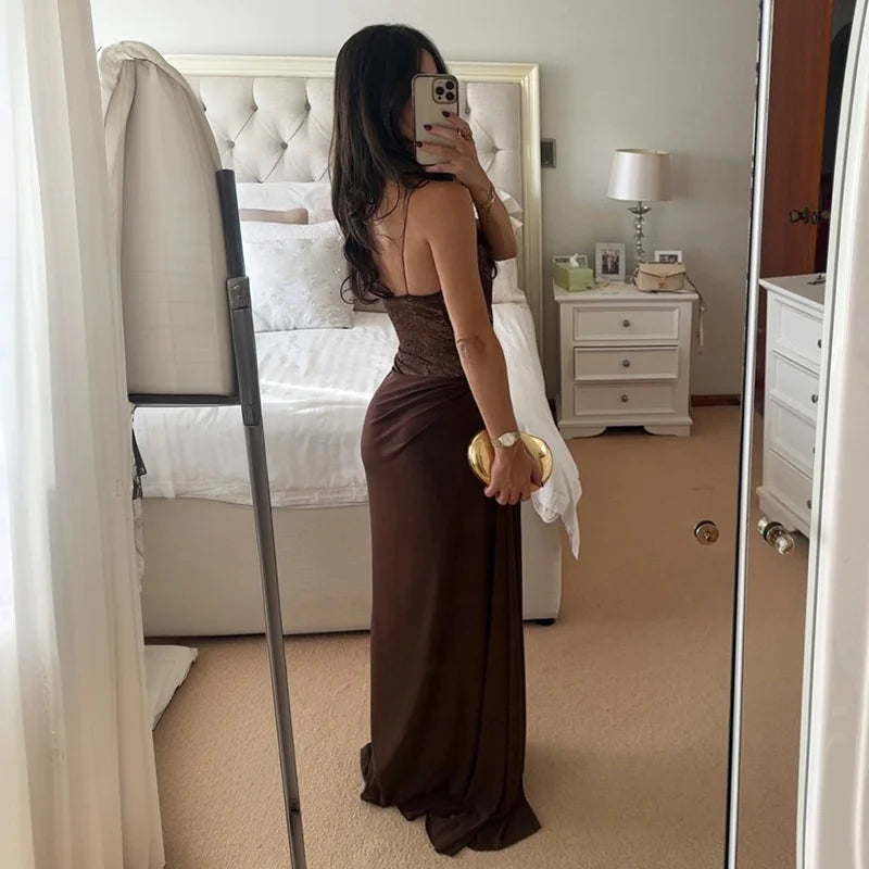 Woman in a brown dress taking a mirror selfie in a bedroom.