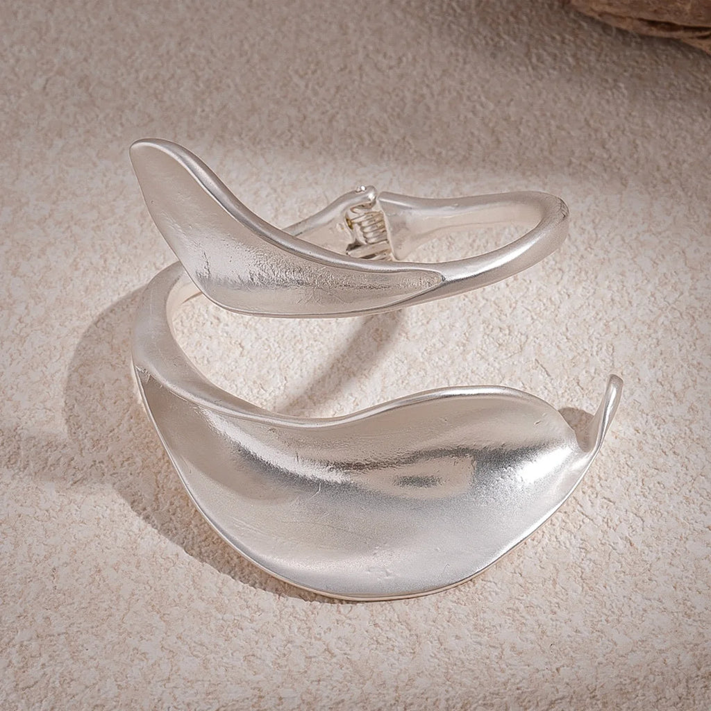 Silver bracelet with a leaf design on a textured beige surface