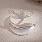 Silver bracelet with a leaf design on a textured beige surface