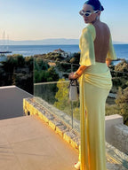 Woman in a yellow dress standing on a balcony with a scenic view of the sea.