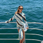 Woman in a striped dress standing on a boat with ocean in the background