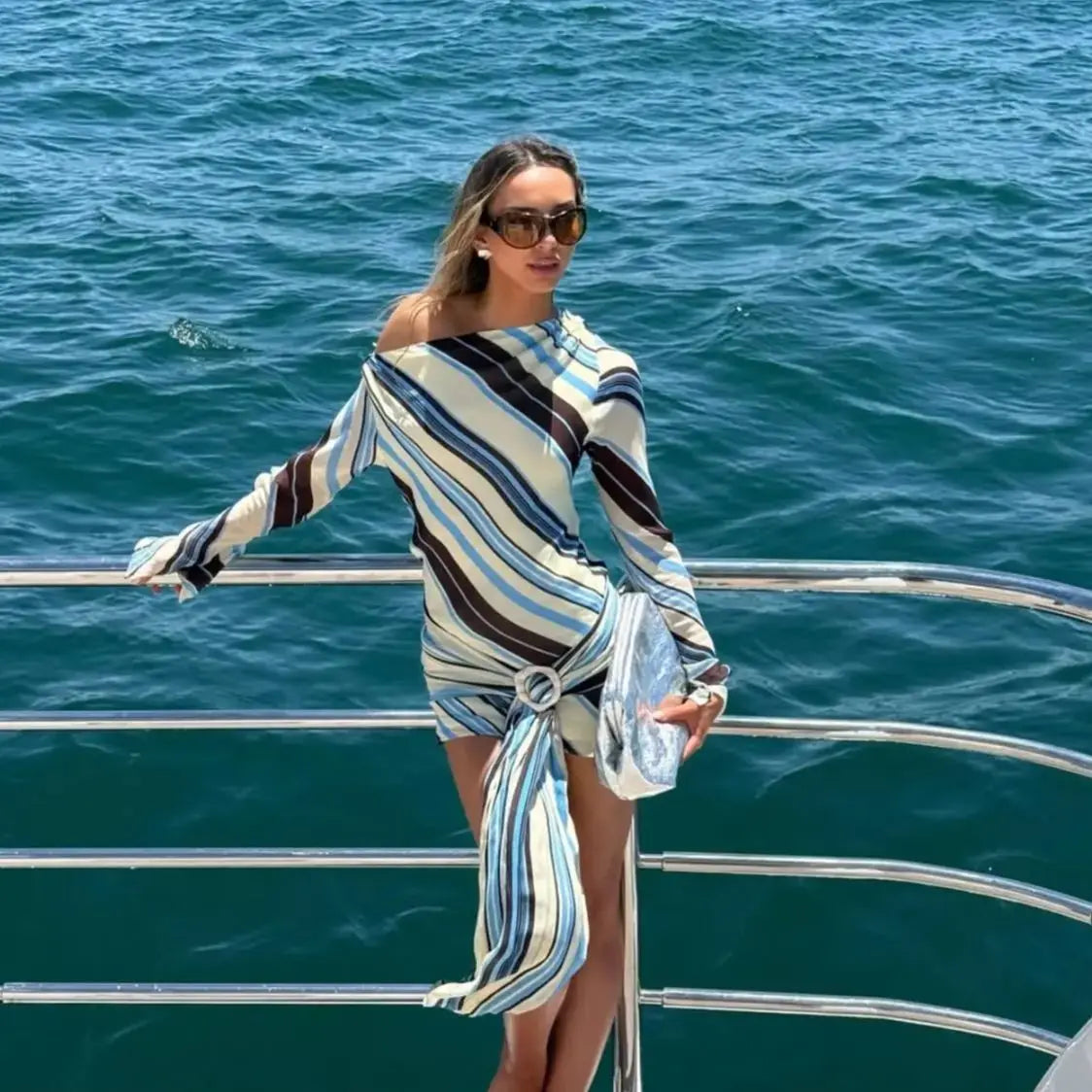 Woman in a striped dress standing on a boat with ocean in the background