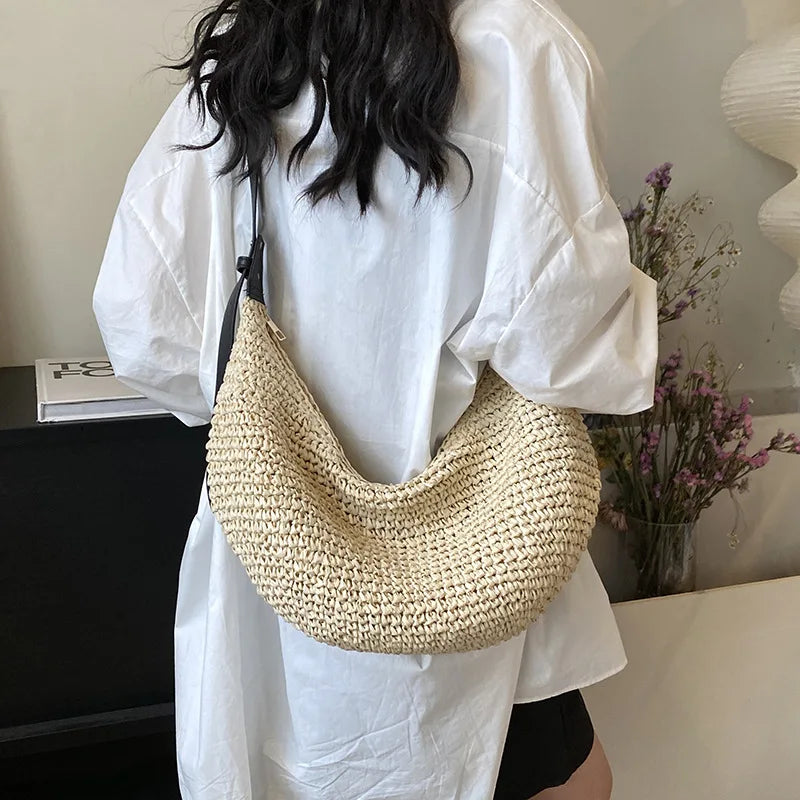 Person wearing a white shirt with a straw bag over their shoulder indoors.