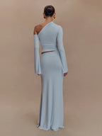 Woman wearing a light blue one-shoulder dress with long sleeves on a beige background