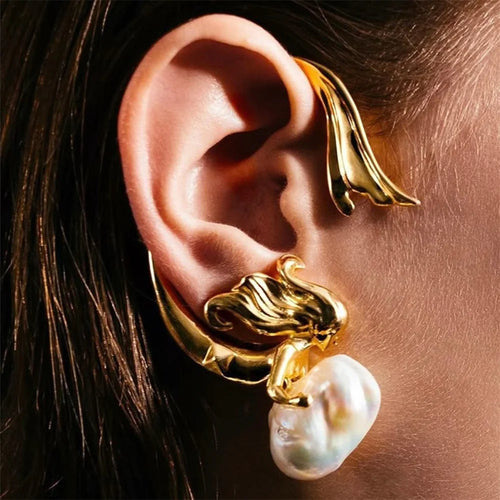 Gold earring with a pearl on an ear, close-up view.