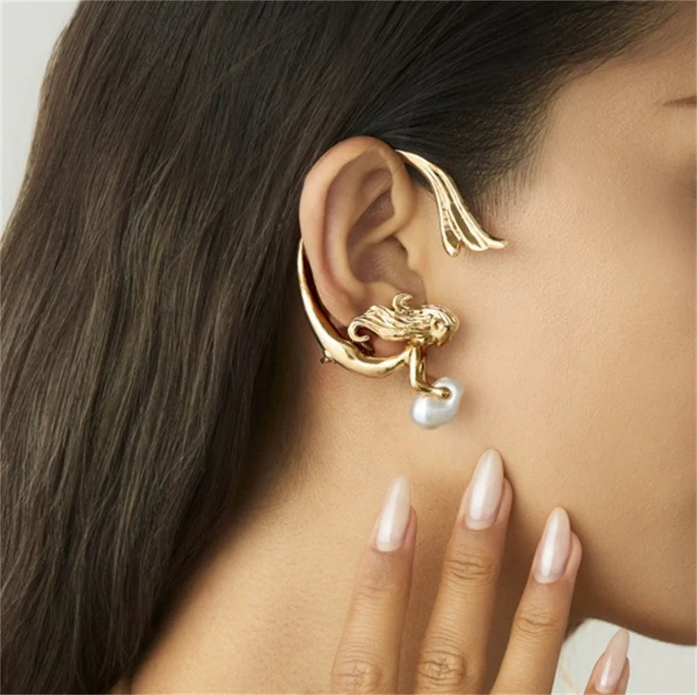 Gold ear cuff with a pearl drop worn by a person with long dark hair.