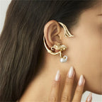 Gold ear cuff with a pearl drop worn by a person with long dark hair.