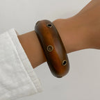 Wooden bracelet on a wrist with a plain background