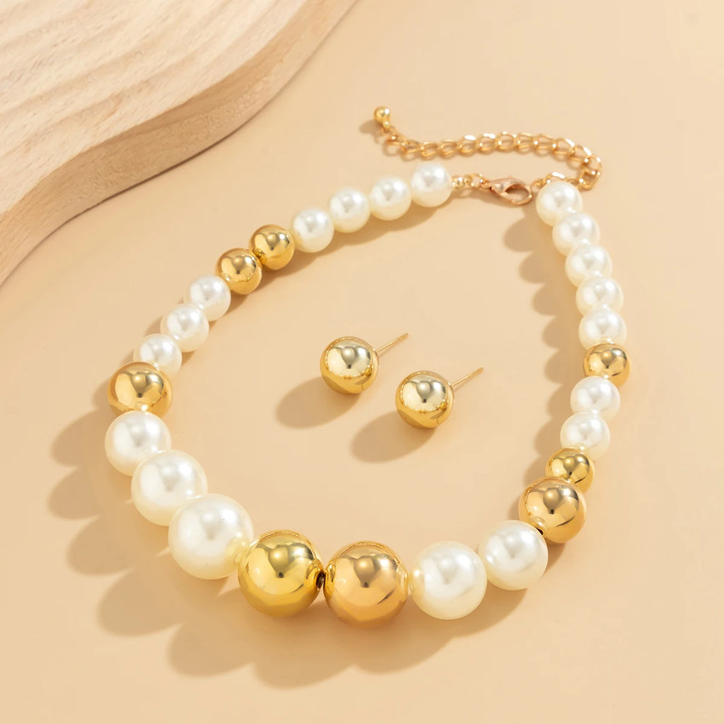 Pearl and gold necklace with matching earrings on a beige background