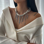 Person wearing a pearl and silver fringe necklace with a white outfit.