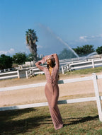 Woman in a striped dress standing in an open field with a fountain in the background