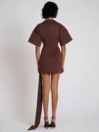 Brown dress with a long train worn by a model on a white background
