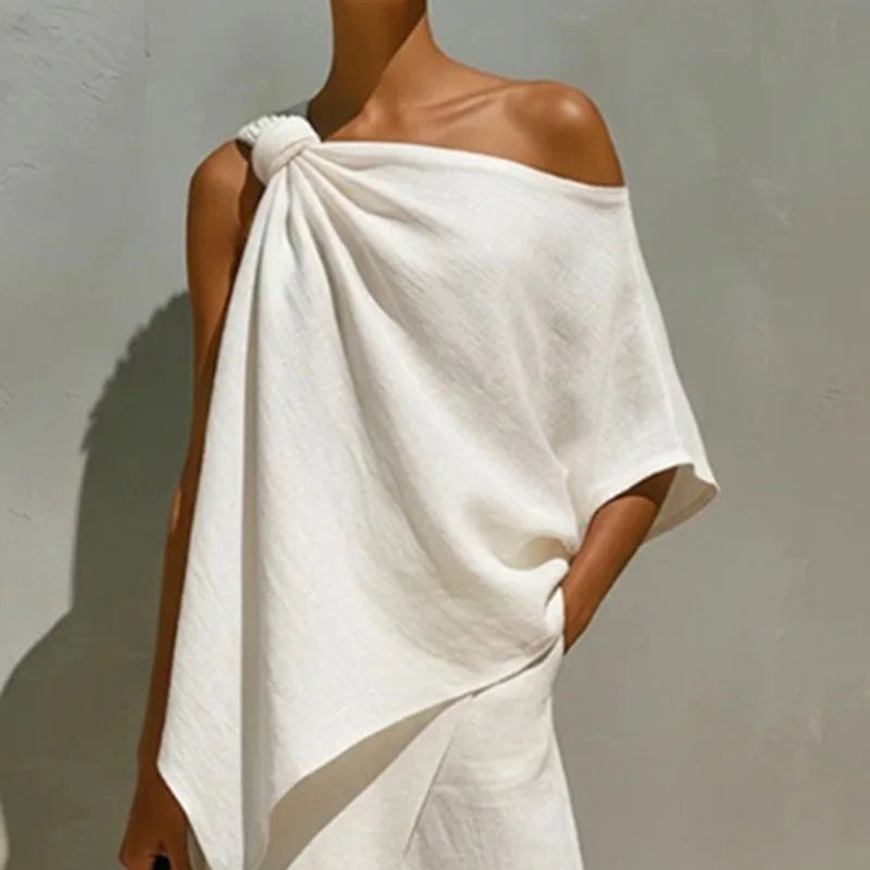 Person wearing a white off-shoulder garment against a plain background