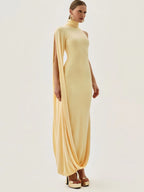 Woman wearing a long, light-colored dress with cape sleeves on a white background