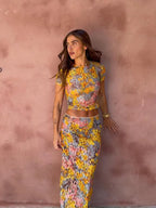 Woman wearing a floral two-piece outfit against a pink wall