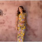 Woman wearing a colorful floral outfit against a textured wall.