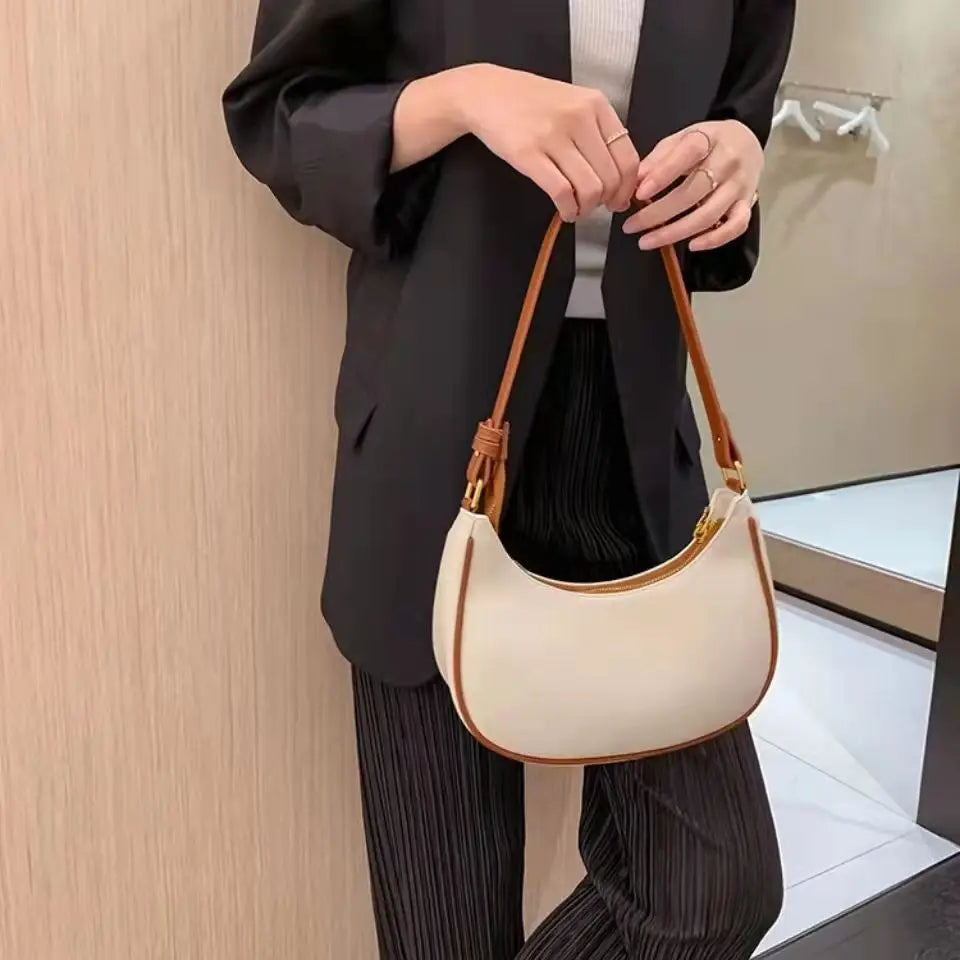Person holding a beige handbag with brown handles against a neutral background