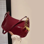 Red handbag with a gold keychain held by a hand against a neutral background