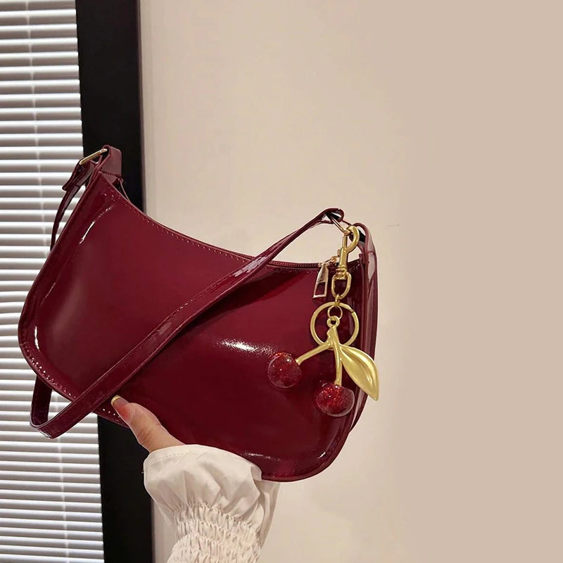 Red handbag with a gold keychain held by a hand against a neutral background