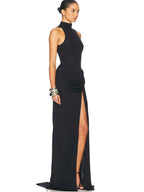 Woman wearing a black evening gown with a high slit on a white background