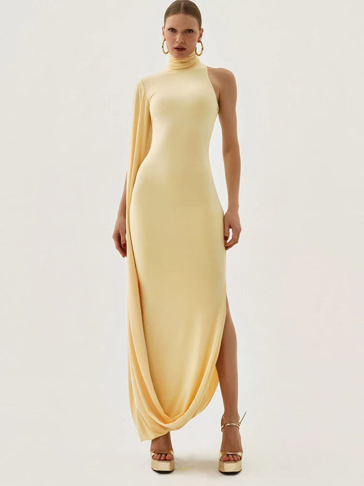Woman wearing a long, light yellow dress with a slit on a white background
