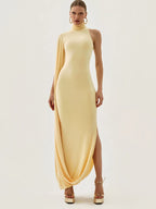 Woman wearing a long, light yellow dress with a slit on a white background